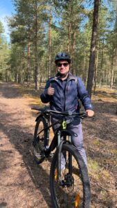 a man standing behind a bike and smiles