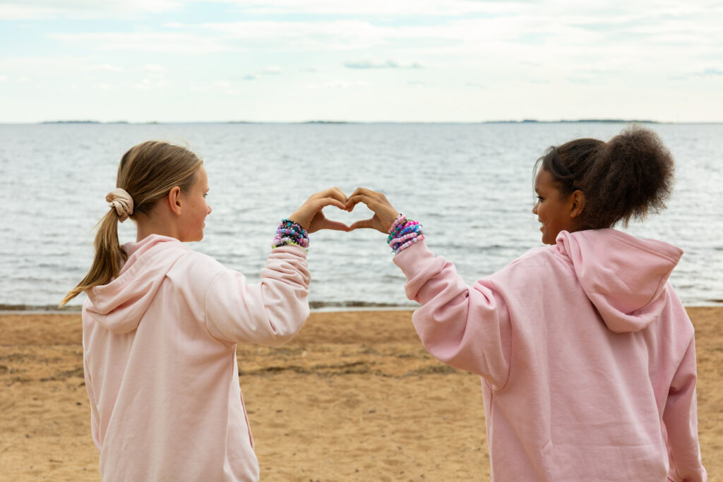 kaksi tyttöä tekee käsillään sydämen
